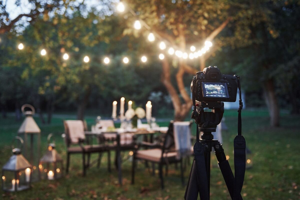 Professional equipment. Camera on the tripod stand in the field in front of prepared table at evening time