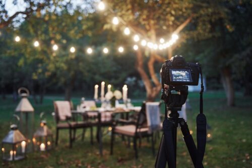 Professional equipment. Camera on the tripod stand in the field in front of prepared table at evening time